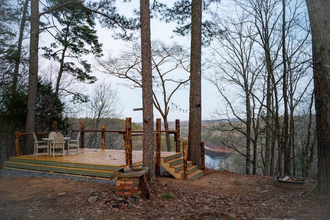 Scenic wooden deck overlooking a river, surrounded by trees in a serene landscape.